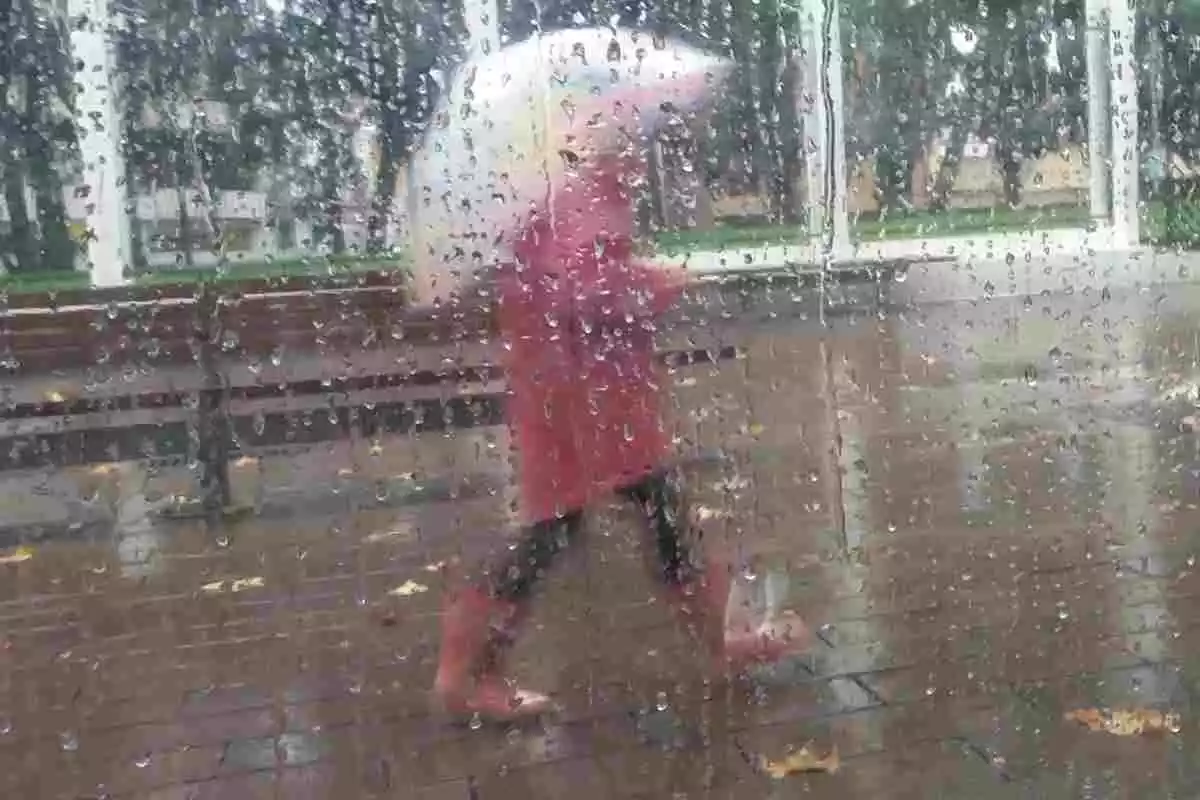 Imatge d'una noia passejant en un dia de pluja de tardor