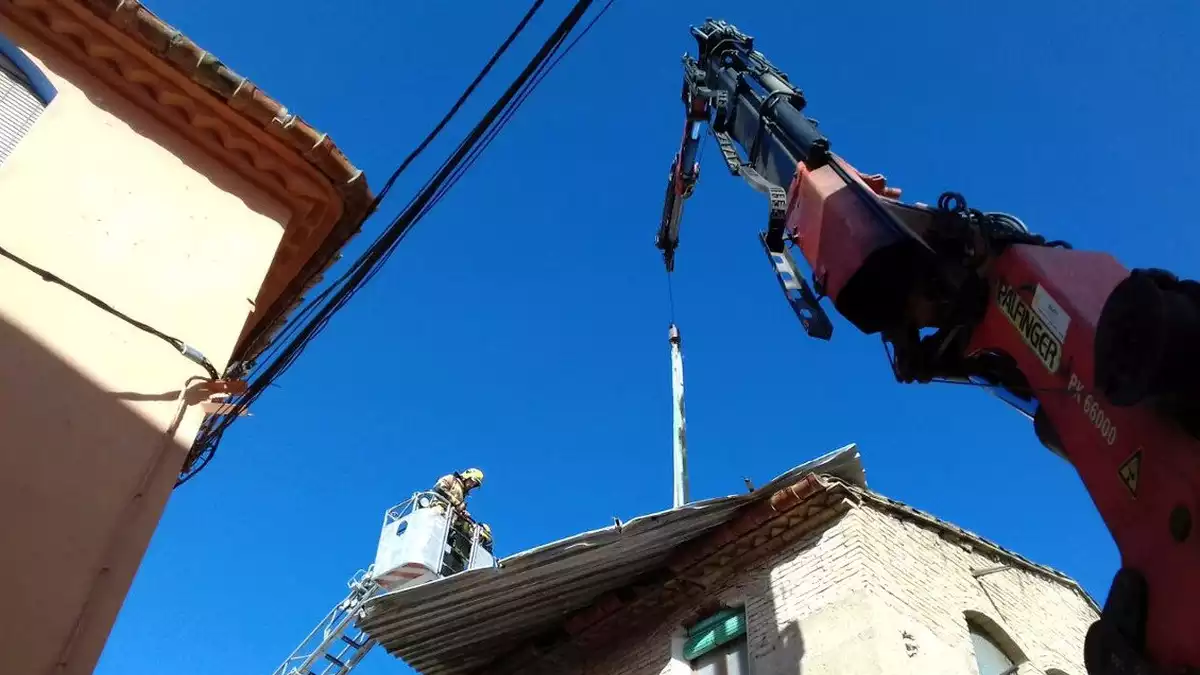 Els Bombers de la Generalitat retirant la teulada metàl·lica de Benissanet amb l'ajuda d'una grua de gran tonatge